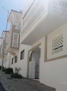 a white building with a door and a balcony at Al Hoceima Hay Bades Villa in Al Hoceïma