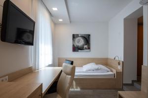 a bedroom with a desk with a bed and a tv at Apartmaji in sobe RaMar in Straža