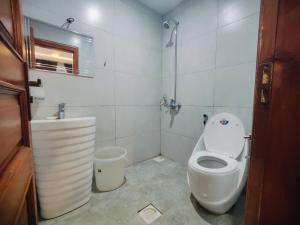 a white bathroom with a toilet and a sink at Snow Stones in Khaira Gali
