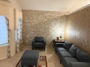 a living room with a couch and chairs and a brick wall at Modern Basement Suit west side with Room 4 in Edmonton