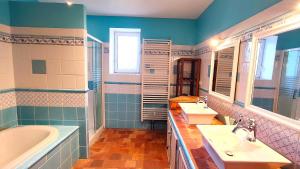 a bathroom with two sinks and a bath tub and a tubermott at Maison d'hôtes Le Rancher in Teloché