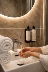 a woman is washing her hands in a bathroom sink at Jainty Apartments Bytom in Bytom +77 photos
