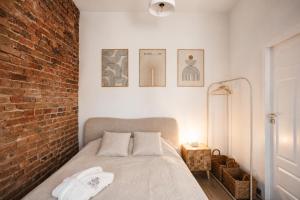 a bedroom with a bed with a brick wall at Jainty Apartments Bytom in Bytom