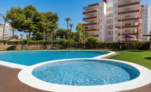 a swimming pool in a resort with a building at Ático vistas al mar in Cullera