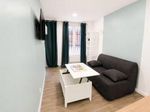 a living room with a couch and a table at Petit cocon moderne Cuisine équipée TV WIFI in Roubaix
