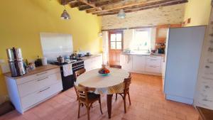 a kitchen with a table and chairs in a room at Maison d'hôtes Le Rancher in Teloché