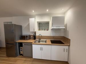a kitchen with white cabinets and a stainless steel refrigerator at Le Grimpeur in Achères-la-Forêt