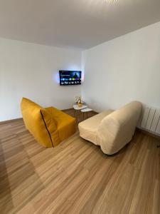 a living room with a yellow couch and wooden floors at Le Grimpeur in Achères-la-Forêt