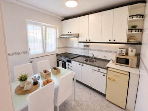 a kitchen with white cabinets and a table with chairs at Abuela Maruja - Piso acogedor en Cee, perfecto para desconectar in Cee