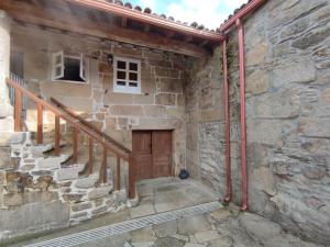 a stone house with a wooden door and stairs at Casa da Torreira Naturaleza y descanso in Galegos
