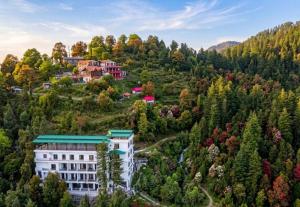 an aerial view of a building on a hill with trees at LA Riqueza Dhanolti View - View of Valleys & Mountains - Private Parking - Near to Eco Park & Surkanda Devi Temple in Dhanaulti