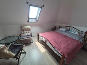 a bedroom with a bed and a chair and a window at Varjas apartman in Ábrahámhegy