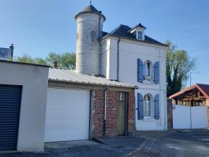 a white house with a chimney and a garage at La petite Tourelle Ruelle de la Fontaine in Péronne