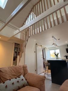 a living room with a couch and a staircase at Little Rozel in East Grinstead