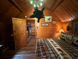 a bedroom in a log cabin with a bed and a chandelier at The Raven in Cosby