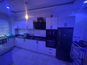 a kitchen with white cabinets and a black refrigerator at Apartments 4B Block B in Lagos