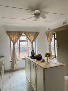 a kitchen with a ceiling fan and some windows at Garden Cottage - Self Catering in Amanzimtoti +4 photos