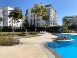 a swimming pool in front of a building at Boho Chic 2BR Retreat Mountain View Executive in New cairo