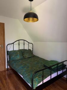 a bedroom with a bed with a green comforter at Całoroczny Domek nad Jeziorem in Białka