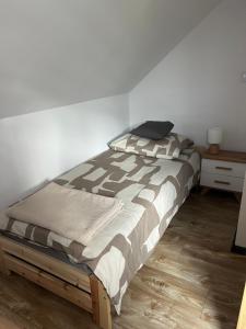a bed in a bedroom with a white wall at Nest Haus in Ludwikowice Kłodzkie