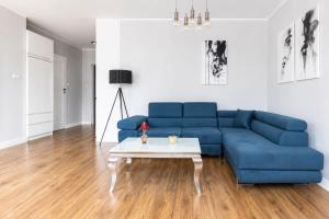 a blue couch in a living room with a table at Apartament Baltic Prestige in Gąski