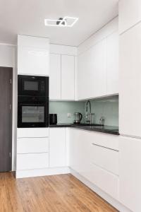 a kitchen with white cabinets and a black microwave at Apartament Baltic Prestige in Gąski
