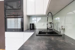 a kitchen with a sink and a microwave at Apartament Baltic Prestige in Gąski