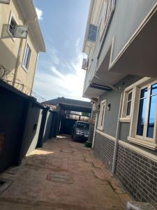 a car is parked in a driveway between two buildings at Asika Luxe Living in Ayobo