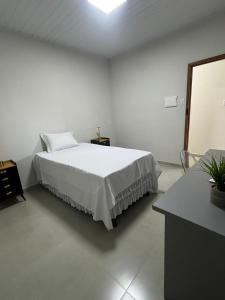 a white bedroom with a bed and a mirror at University Suítes in Carmópolis