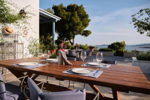 a wooden table with plates and wine glasses on a patio at Villa Irini in Porto Heli