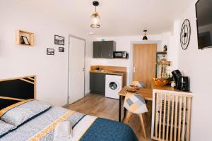 a bedroom with a bed and a desk and a kitchen at Chez Coco - Studio à 200m de la Gare ! in Besançon