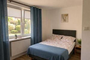 a bedroom with a bed with blue curtains and a window at Apartamenty Raszyn in Raszyn