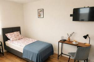 a bedroom with a bed and a desk and a television at Apartamenty Raszyn in Raszyn +12 photos