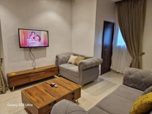 a living room with a couch and a tv on the wall at Nest Nova in Alagbado