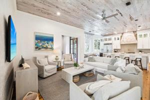 a living room with white furniture and a kitchen at Serenity Now in Rosemary Beach