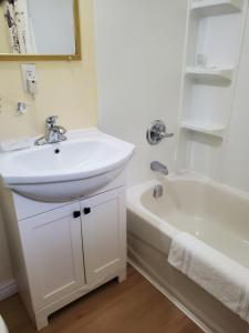 a white bathroom with a sink and a tub and a sink at Carolyn Beach Inn in Thessalon +85 photos