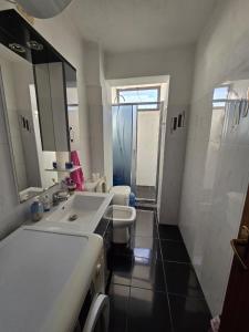 a white bathroom with two sinks and a shower at Duomo Apartament in Shkodër