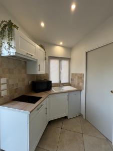 a kitchen with white cabinets and a sink at Le Nid d'escale in Tillé +1 photo