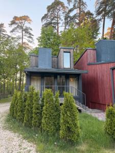 a house with a red wall and trees at Shells & Pines in Jūrmala