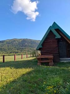 a small log cabin with a bench in a field at Cottage MANSION in Žabljak