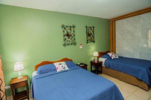 a bedroom with two beds and green walls at Hotel Divisamar by LHR in Manuel Antonio