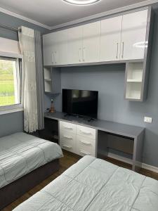 a bedroom with a bed and a desk with a television at Prive Home in Maliq