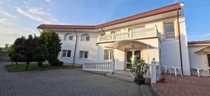 a large white house with a balcony and a driveway at PENZION EUROPA Diakovce in Diakovce