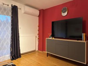 a living room with a flat screen tv on a red wall at Apartmani Hrastik 2 in Bihać