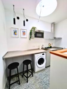a kitchen with a washing machine and two stools at Eva Urban Rooms Centro Lecco in Lecco