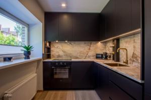 a kitchen with black cabinets and a sink and a window at Uus Street Apartment, Modern Stay near City Centre with Free Parking in Tartu