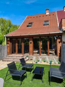 a group of chairs sitting on the grass in front of a house at Miliő Apartman Sarud in Sarud