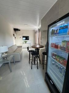 a living room with a refrigerator and a table with chairs at University Suítes in Carmópolis