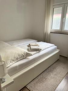 a white bed in a white room with a window at Apartman Orkic in Vodnjan