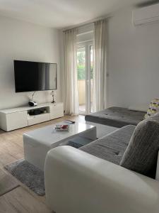 a white living room with a tv and a couch at Apartman Orkic in Vodnjan